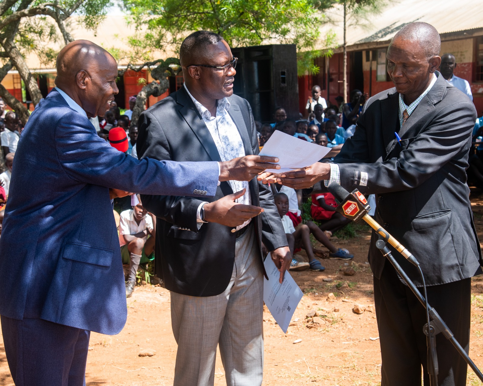 The two Cabinet Secretaries issuing cheques to several schools