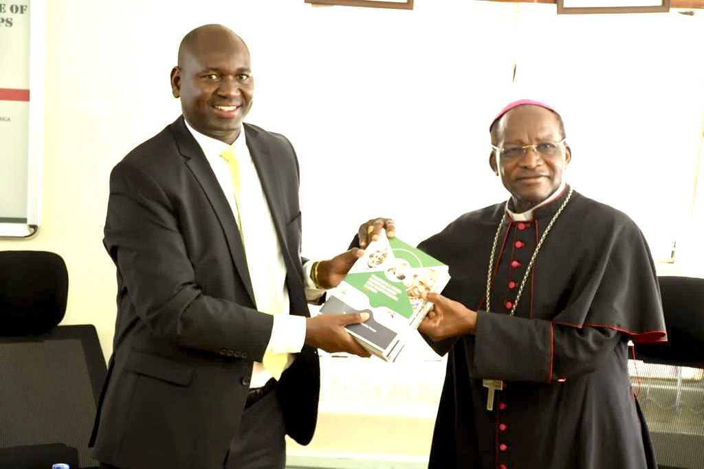 PS Julius Bitok hands over copies of Digital ID FAQ booklet to Kenya Conference of Catholic Bishops chairman Archbishop Martin Kivuva